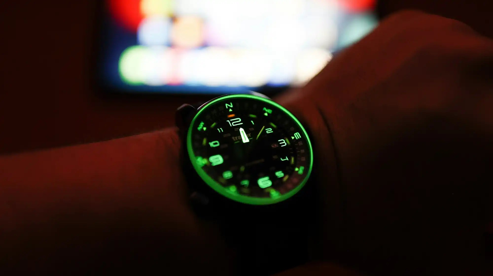 Illuminated wristwatch on wrist.