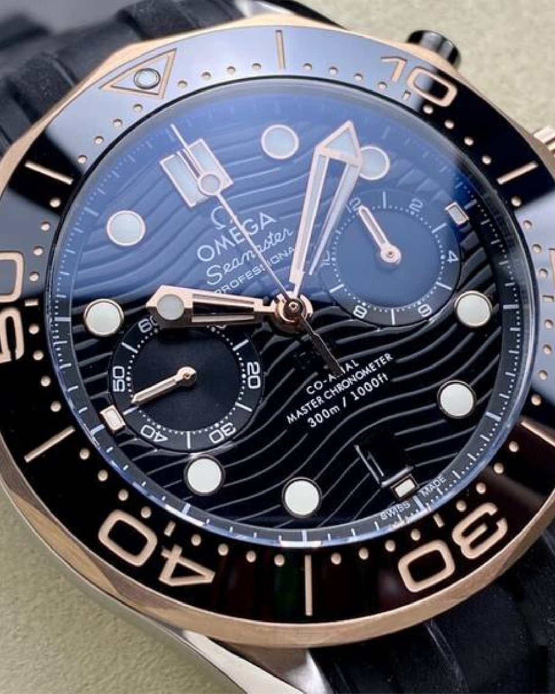 Omega Seamaster 44mm Diver 300m watch with black dial, rose gold bezel, chronograph sub-dials, and black rubber strap