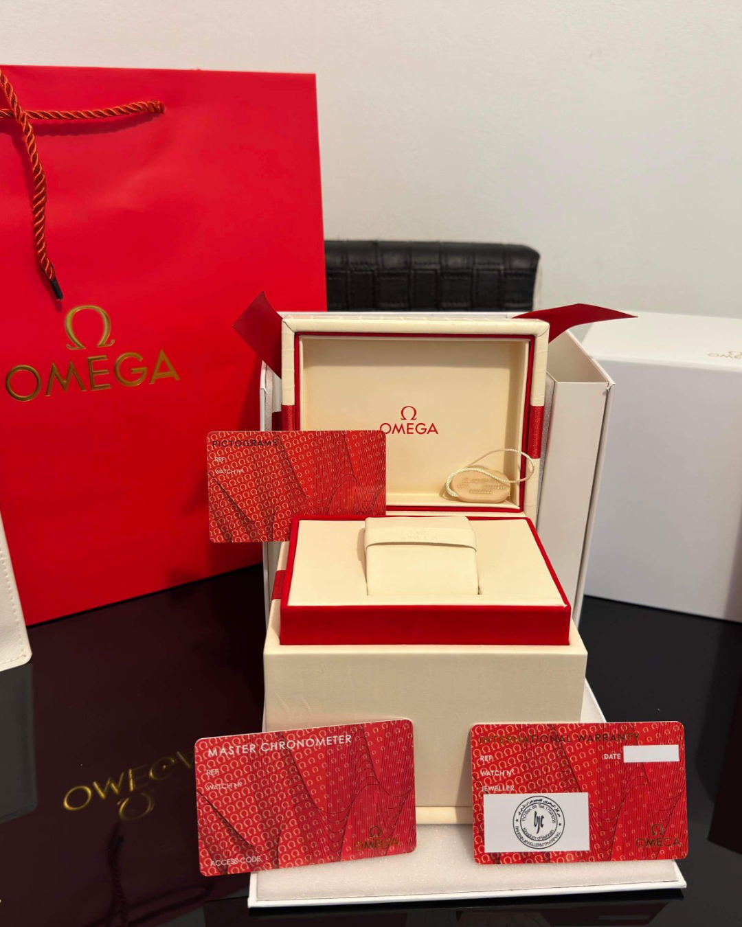 Omega Watch Box with red gift bag and warranty cards for secure luxury watch storage and display